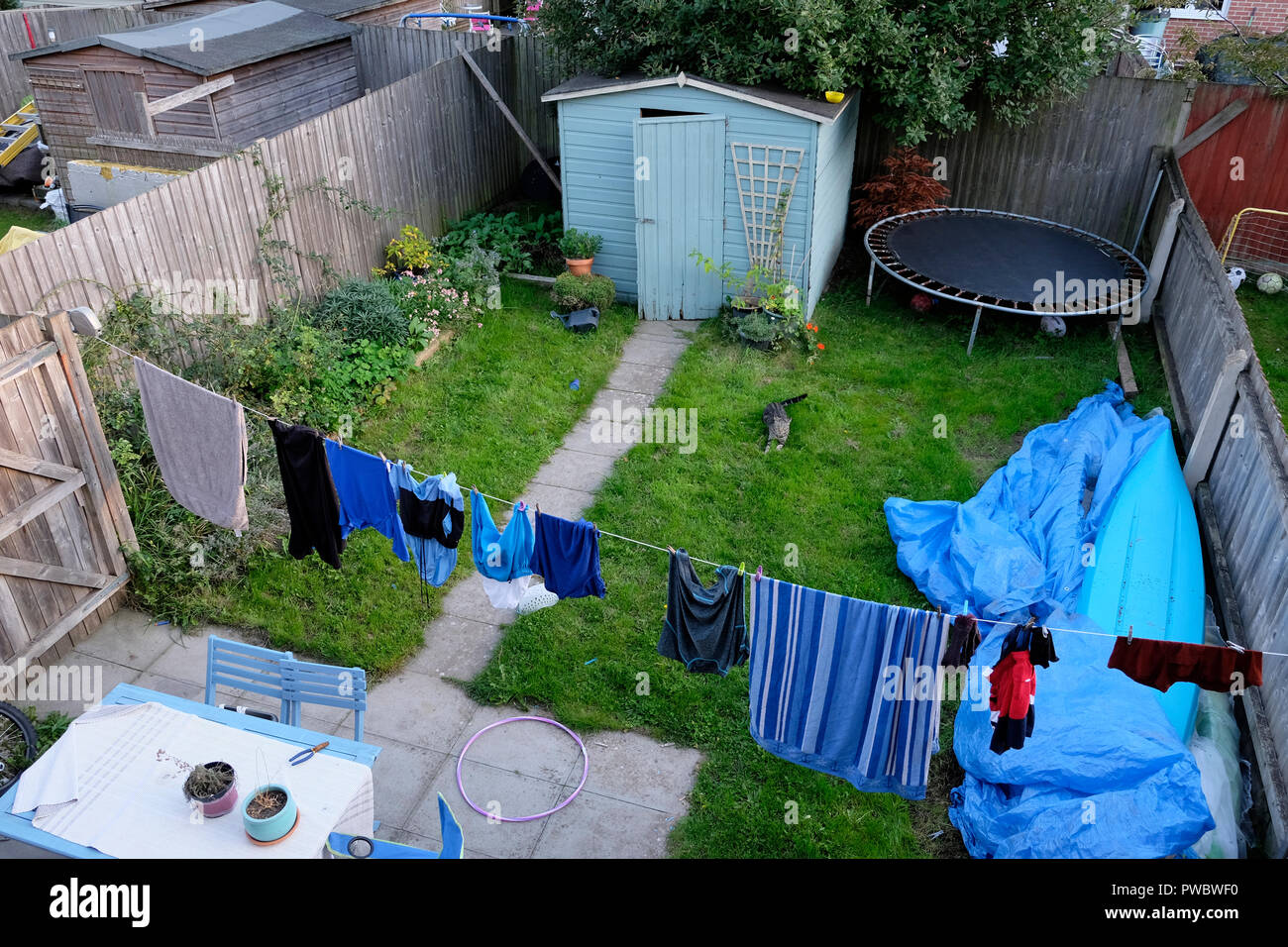 Back garden of a new build house with clothes hanging on washing line, shed, kids trampoline, kayak & plants growing in Cardiff, Wales UK KATHY DEWITT Stock Photo