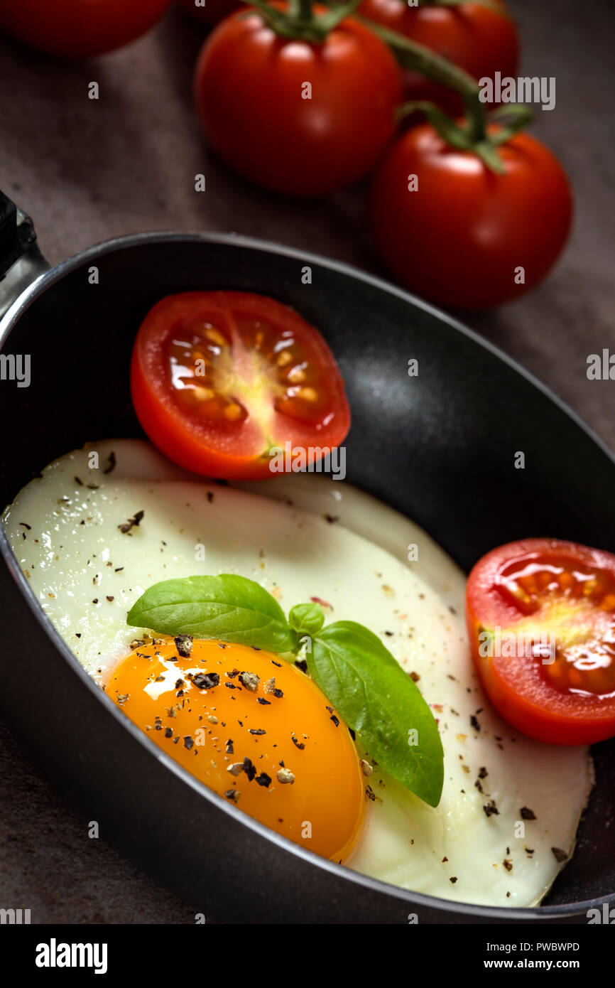 One egg in a little pan with cherry tomatoes and ground pepper Stock Photo