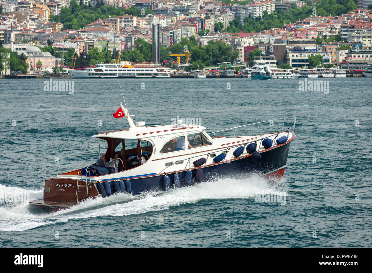 A small power boat sails on the Bosphorus with passengers in the rear, Istanbul, Turkey Stock Photo