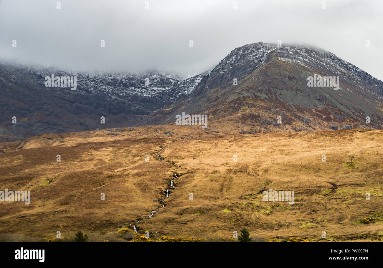 Waterfall running from the snow capped mountains, Black Cuillin mountain rangen, Isle of Skye, Scotland, Uk Stock Photo