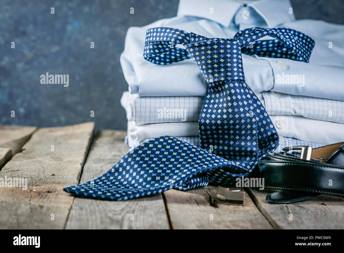 Selection of male clothes - stack of folded shirts, tie, belt ...