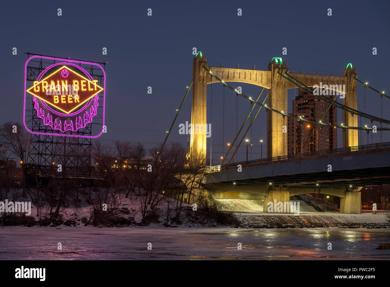 Historic Grain Belt Beer sign and Hennepin Avenue bridge along the Mississippi River in downtown Minneapolis, Minnesota. The sign is lit in Purple and Stock Photo