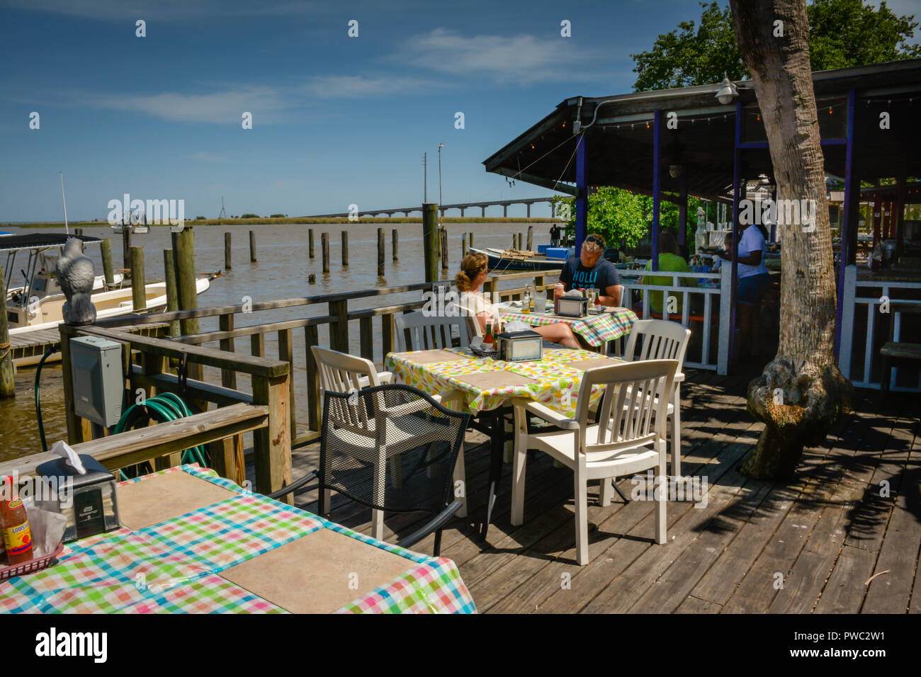 People enjoy the waterfront rustic patio dining at Boss Oyster Restaurant  in Apalachicola, FL,on the bay in the style of Old Florida on Panhandle Stock Photo
