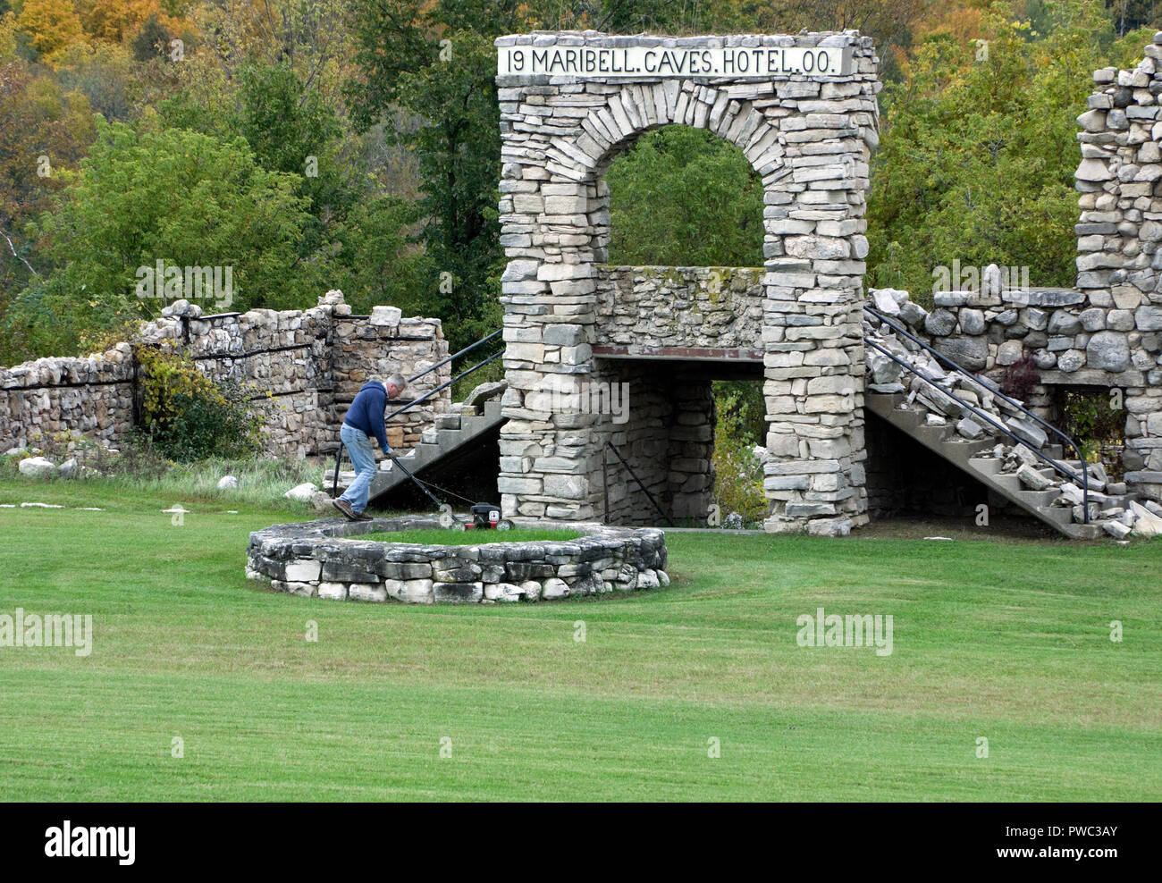 Caretaker mowing grass in circular fountain foundation in front of ruins of historic Maribel Hotel Stock Photo