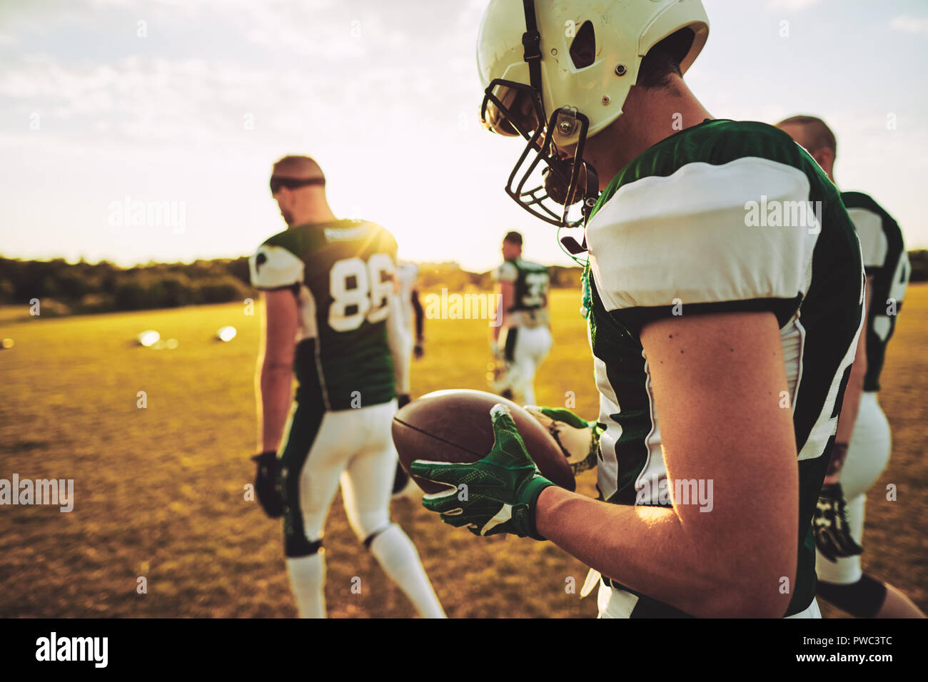 American football quarterback and his teammates walking off a field together after a practice on a sunny afternoon Stock Photo