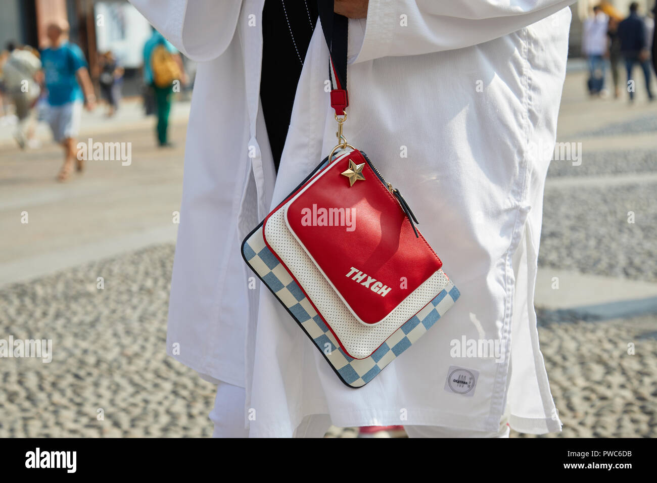 MILAN, ITALY - SEPTEMBER 20, 2018: Man with white, large jacket and red, blue and white bag with golden star before Genny fashion show, Milan Fashion  Stock Photo