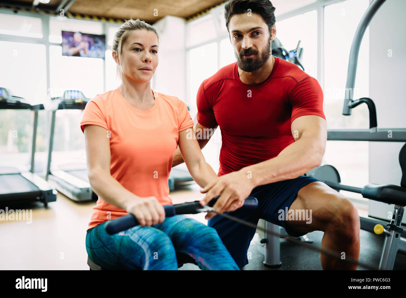 Young beautiful woman doing exercises with personal trainer Stock Photo