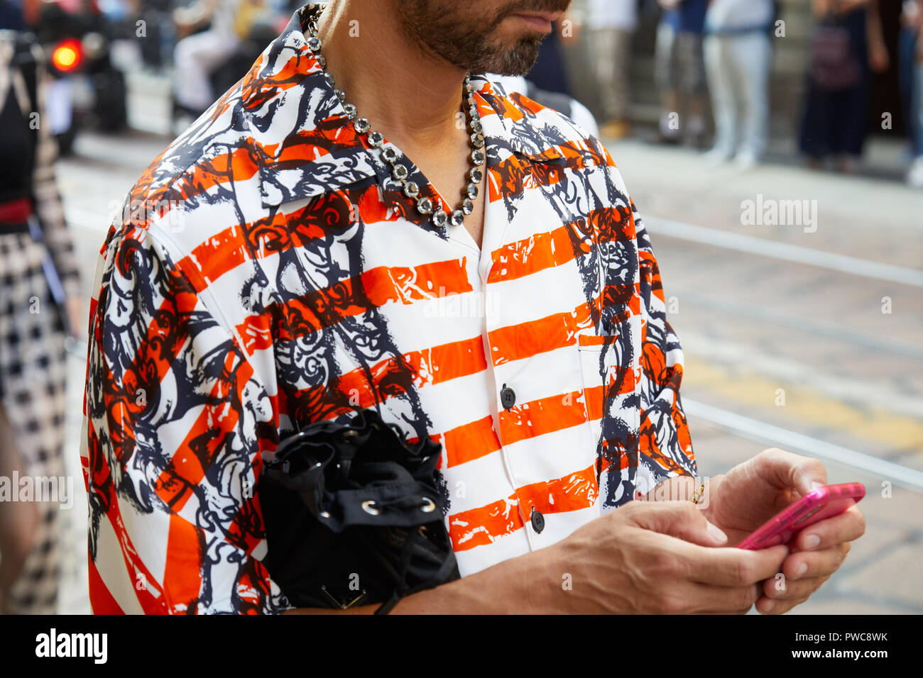MILAN, ITALY - SEPTEMBER 20, 2018: Man with white and orange striped shirt  and necklace looking at smartphone before Vivetta fashion show, Milan Fashi  Stock Photo - Alamy