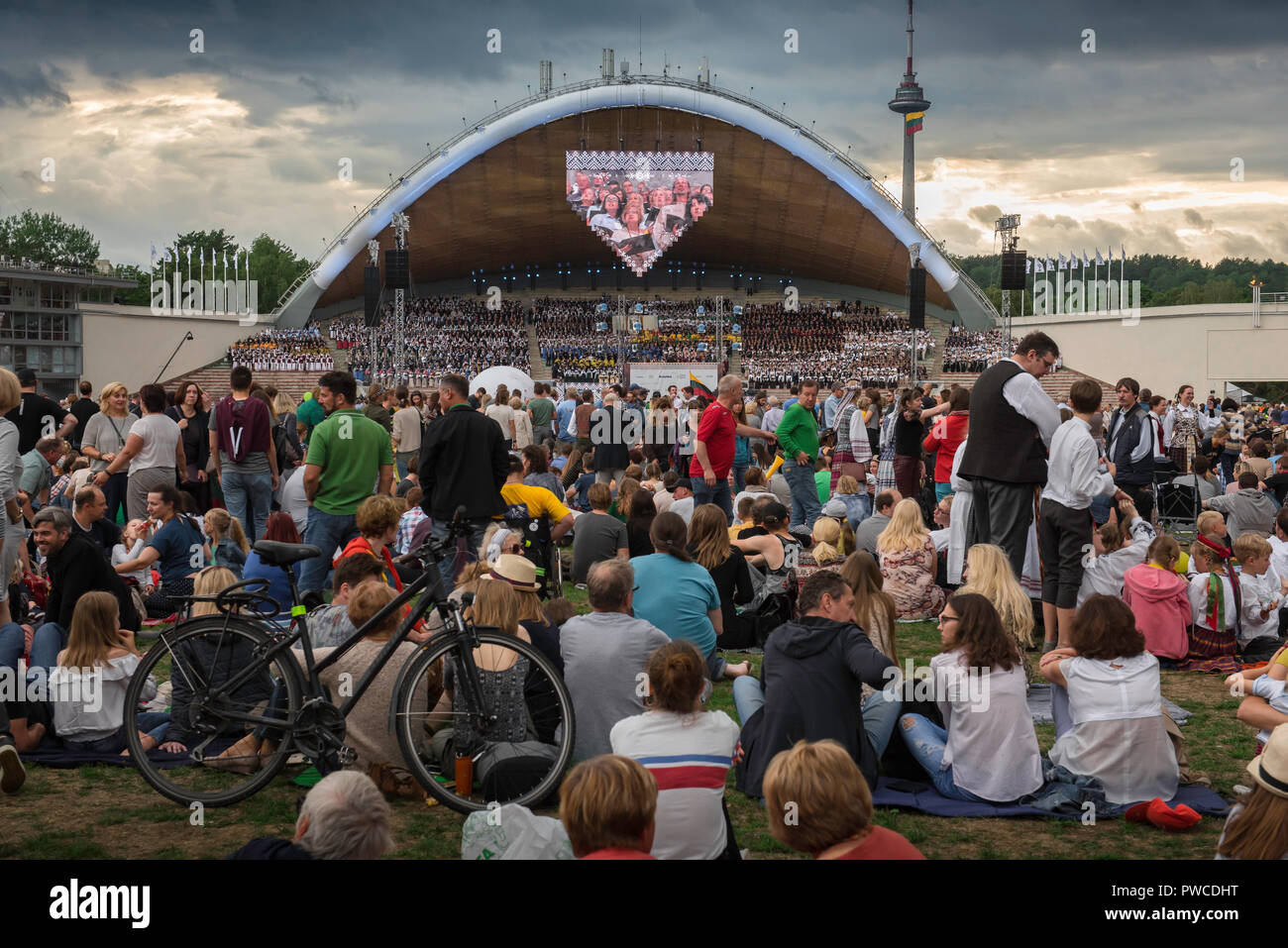 Lithuania people, view of people gathered at dusk in front of the Vingis Park amphitheatre during the Lithuanian Song And Dance Festival in Vilnius. Stock Photo