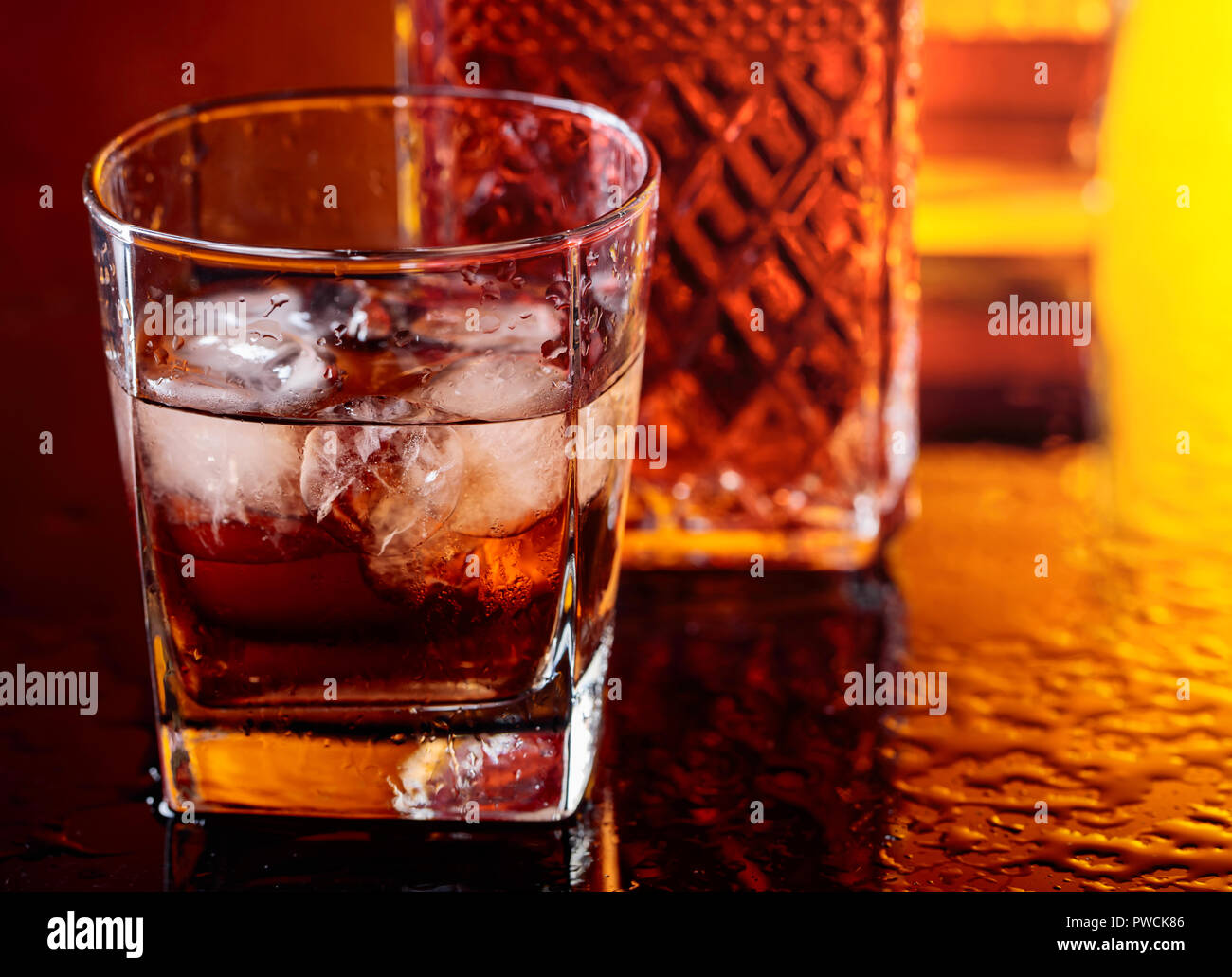 Glass of scotch whiskey with natural ice on table in bar Stock Photo ...