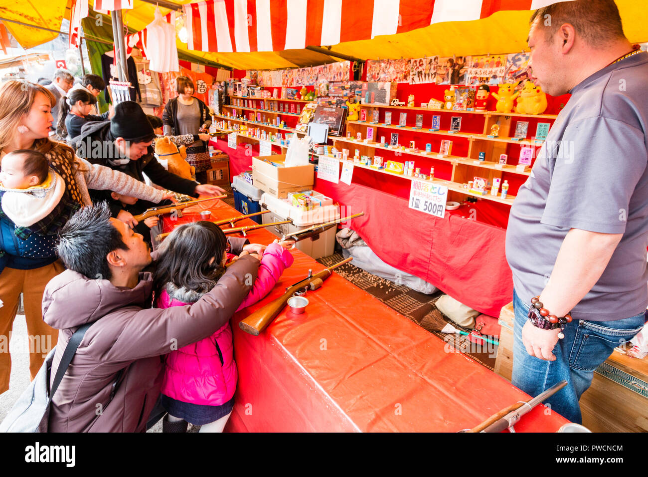 Japanese children's shooting gallery at stall during festival. Father