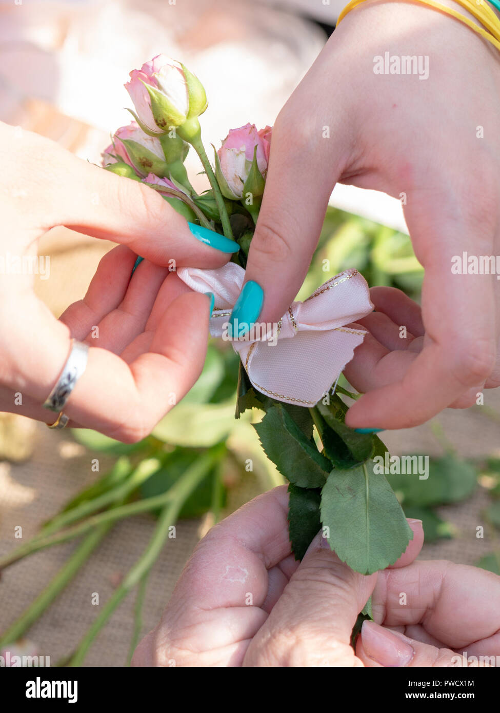 Female hands tie a ribbon on a bouquet of flowers. Stock Photo