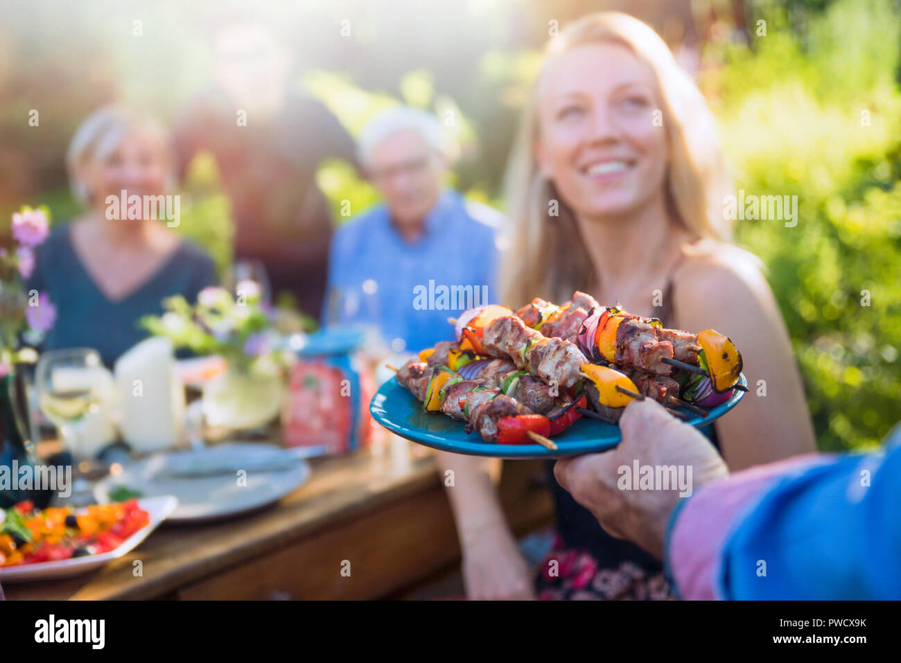 cheerful family gathered around a table for a bbq in the garden Stock Photo