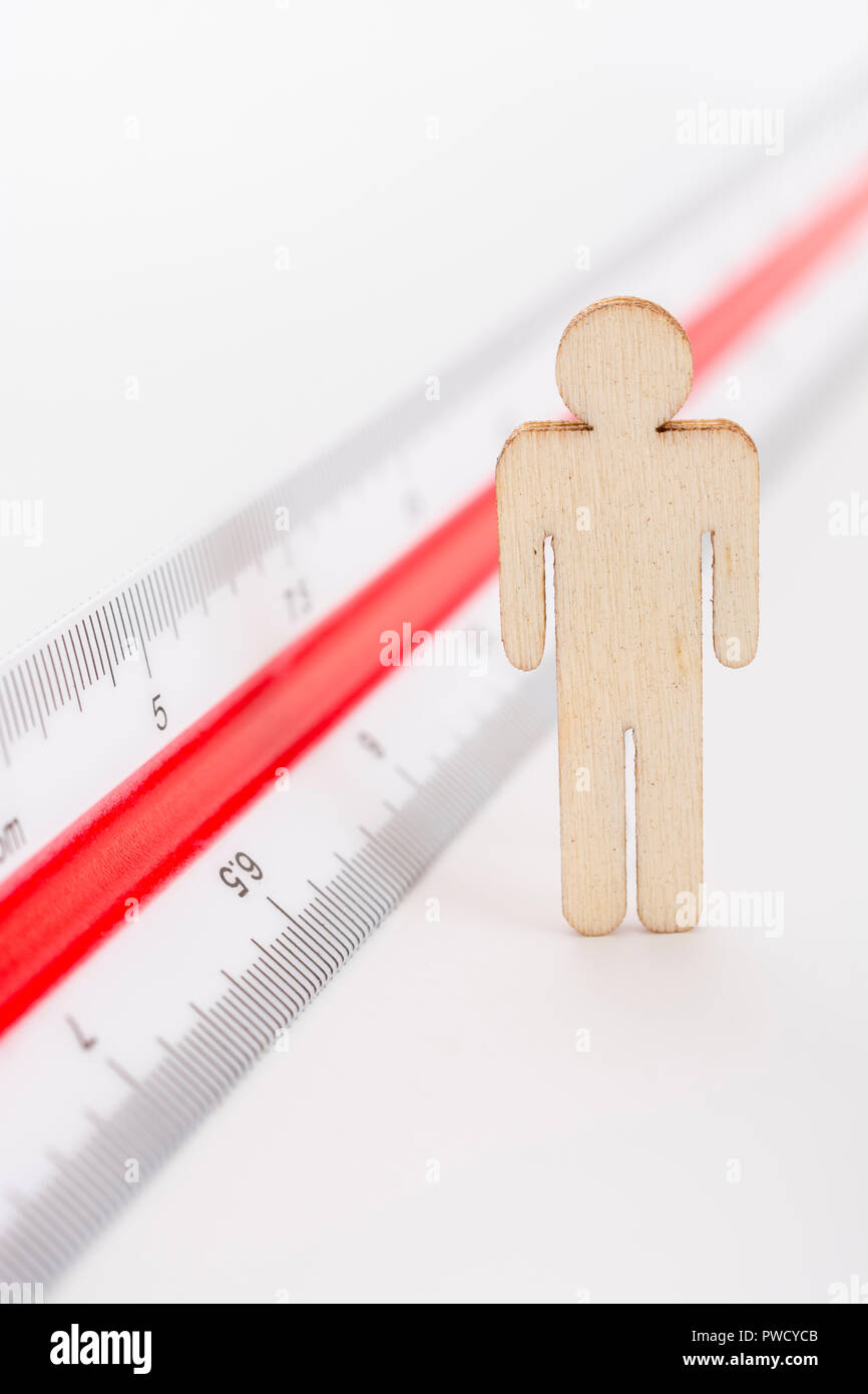 Macro small laser-cut wooden figure and ruler. Metaphor measuring personal performance, demographics concept, productivity, get the measure of a man. Stock Photo