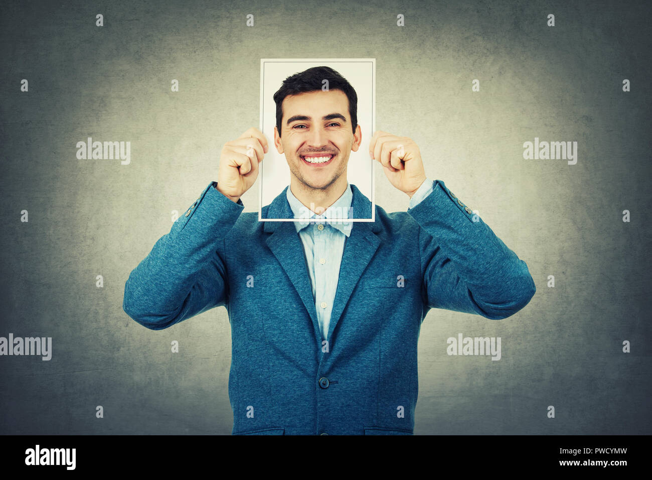 Businessman covering his face using a paper photo with self portrait sketch, like a mask for hiding the true emotion. Private life, faceless personali Stock Photo