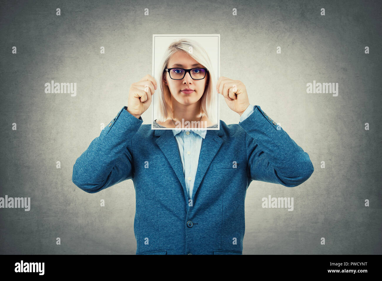 Businessman use a woman portrait as undercover, hiding his face behind photo sheet, like a fake mask. Private life, split personality and unreal ident Stock Photo