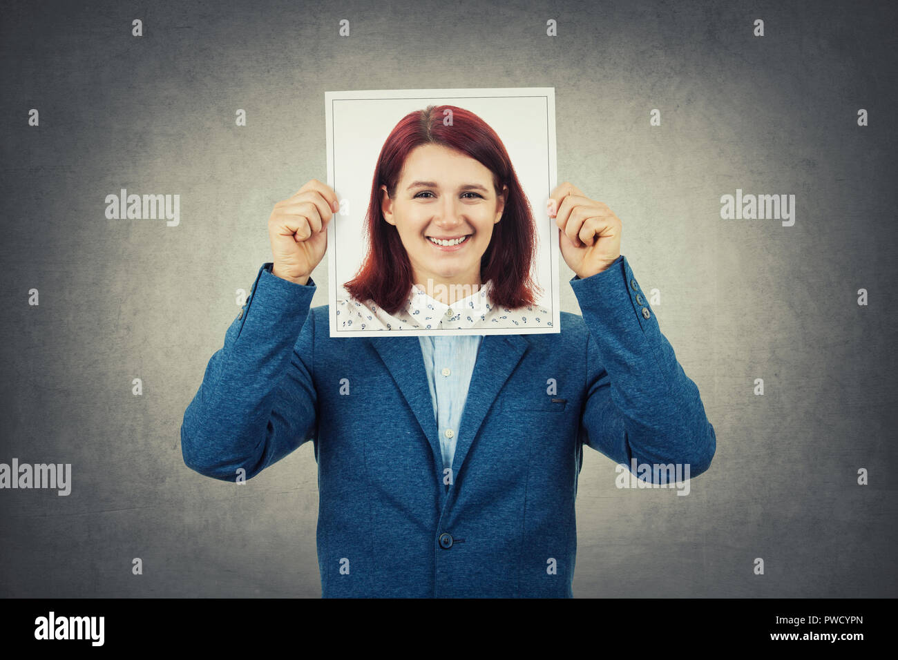 Man covering his face using a woman portrait, like a mask for hiding his identity. Business undercover, hide behind fake personality. Stock Photo