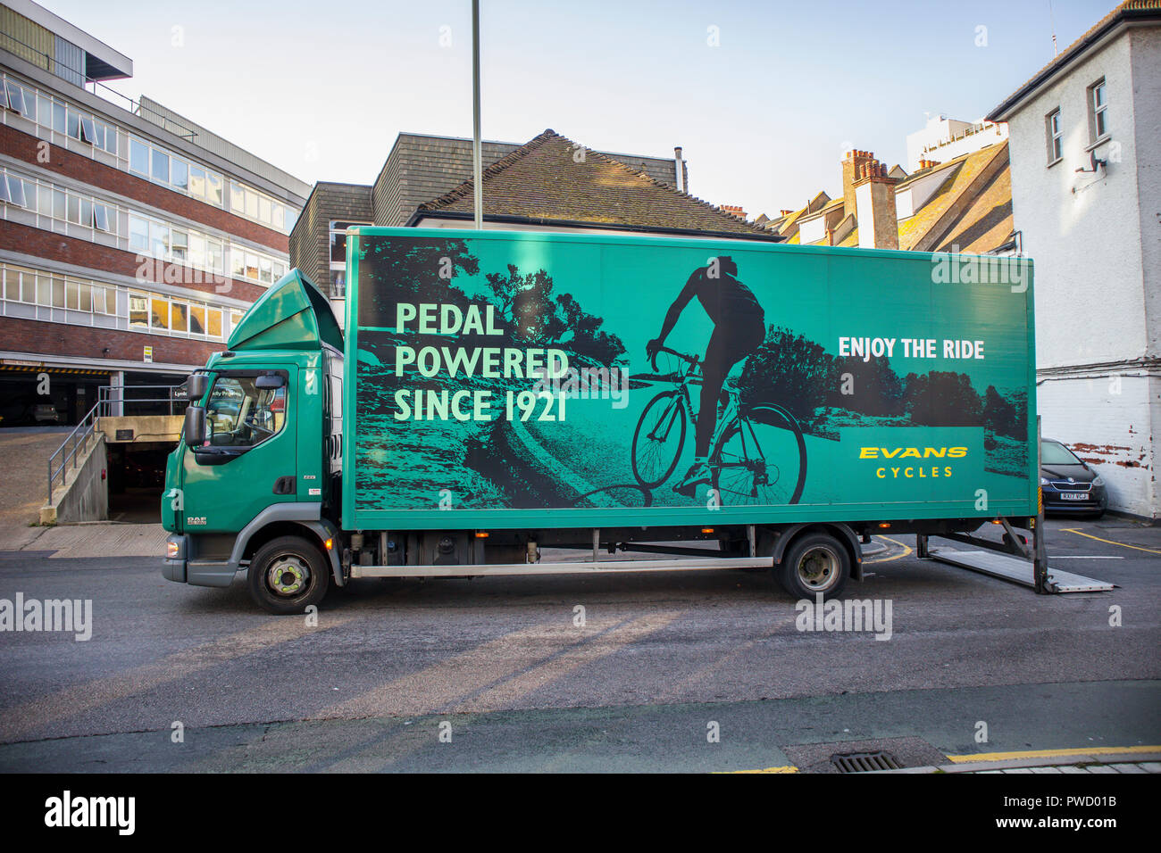 Large Evans Cycles green delivery lorry in Evans Cycles livery parked on the roadside making a delivery to their shop in Woking, Surrey, UK Stock Photo