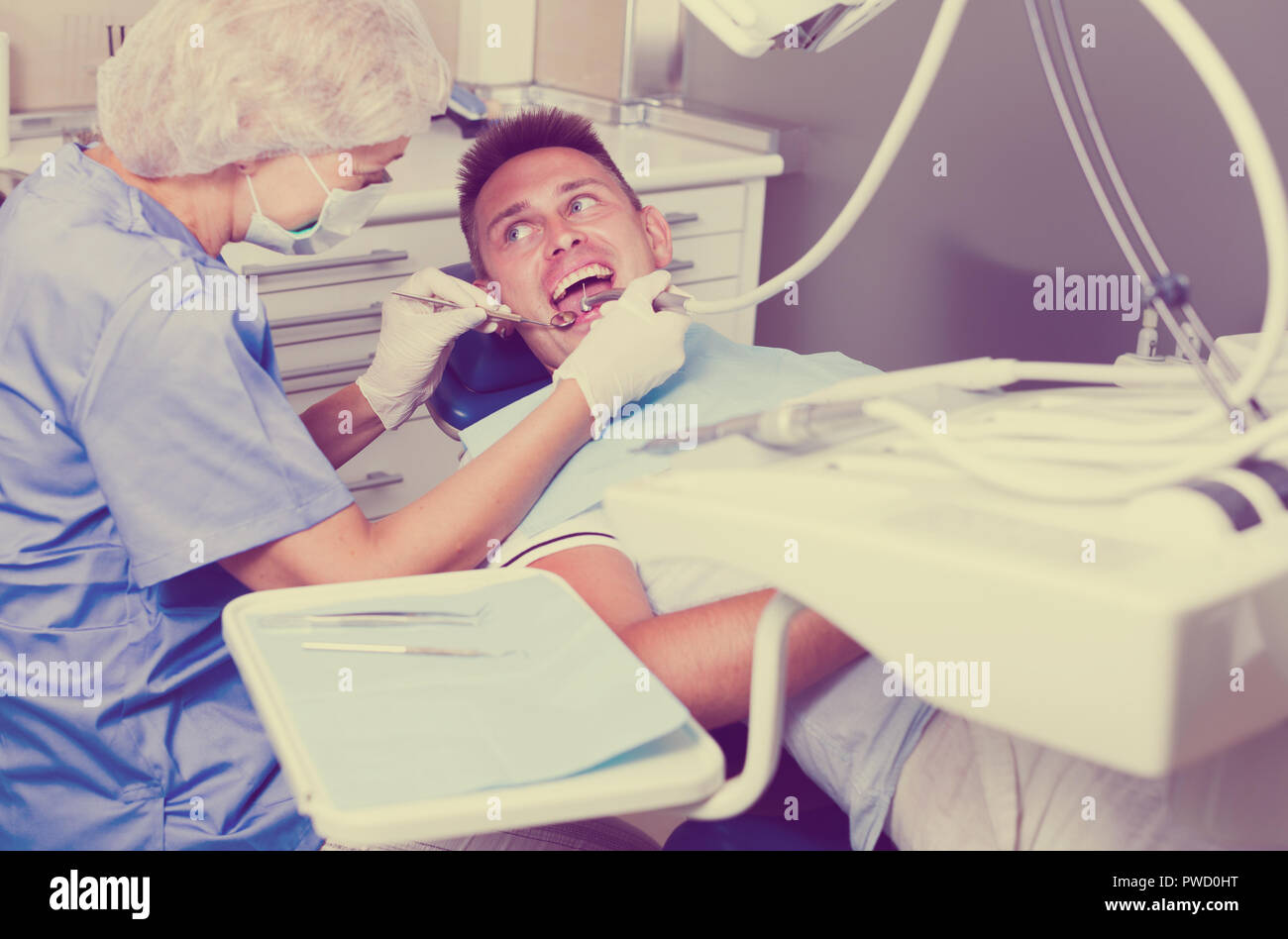 Male patient sitting on chair in dental office getting dentist ...