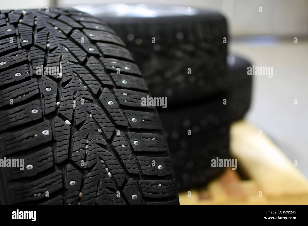 Snow tires with metal studs in garage. Small stones in the groove. Close up image, shallow depth of field. Stock Photo