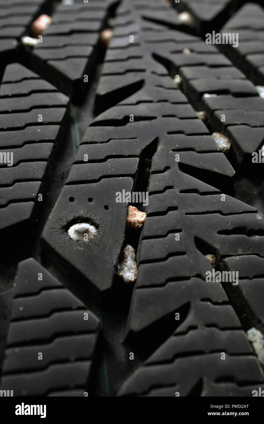 Used snow tire with metal studs close up. Vertical background image. Stock Photo