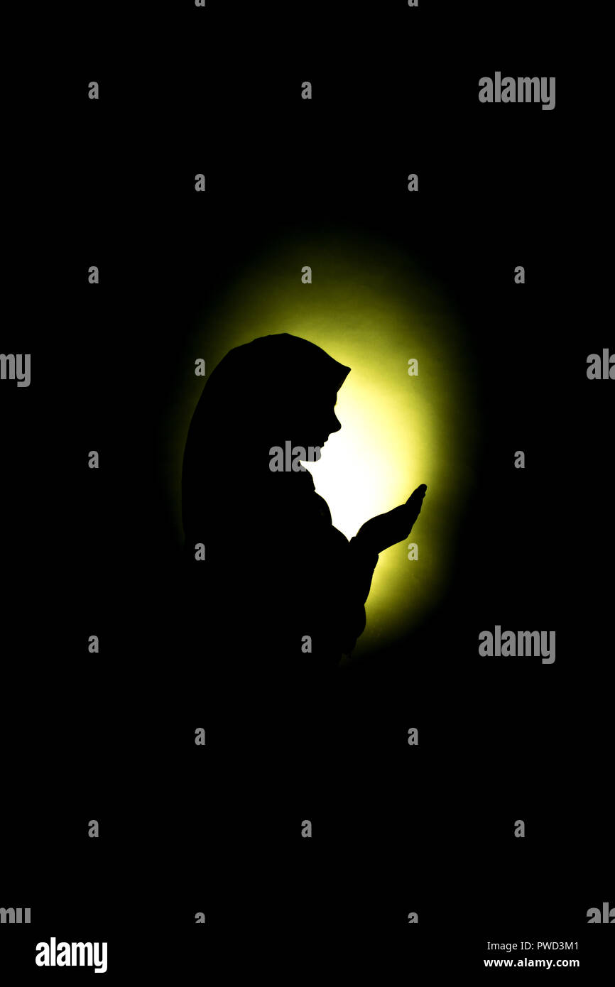 Silhouette Of A Muslim Woman Praying To Allah Stock Photo