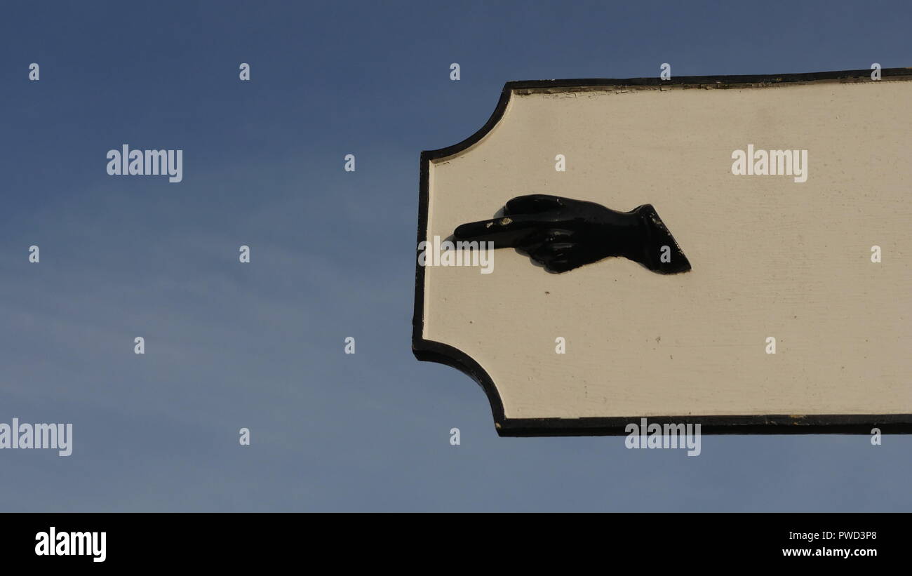 Sign post pointing left. A black hand on a sign post pointing left direction. Stock Photo