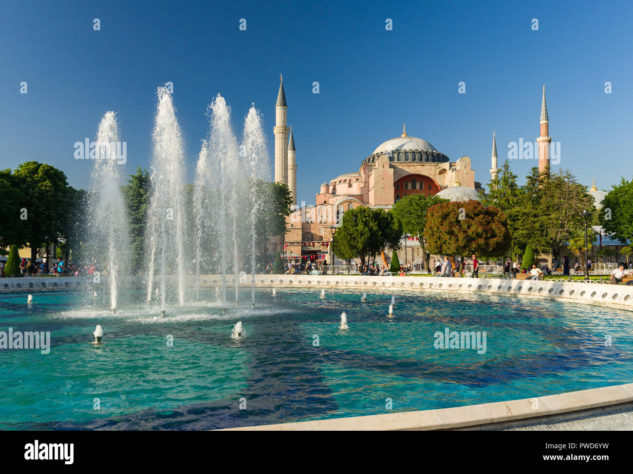 A large water fountain with Hagia Sophia museum and tourists walking in ...