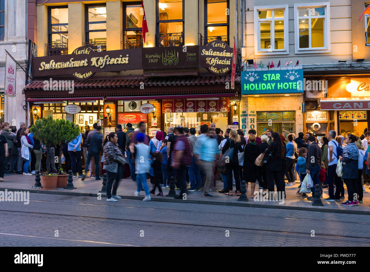 A long queue of people waiting to buy food from restaurant as dusk sets