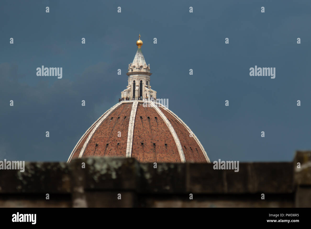 Parts of the Duomo peak over the wall at an outdoor cafe at the Uffizi Gallery in Florence, Italy. Stock Photo