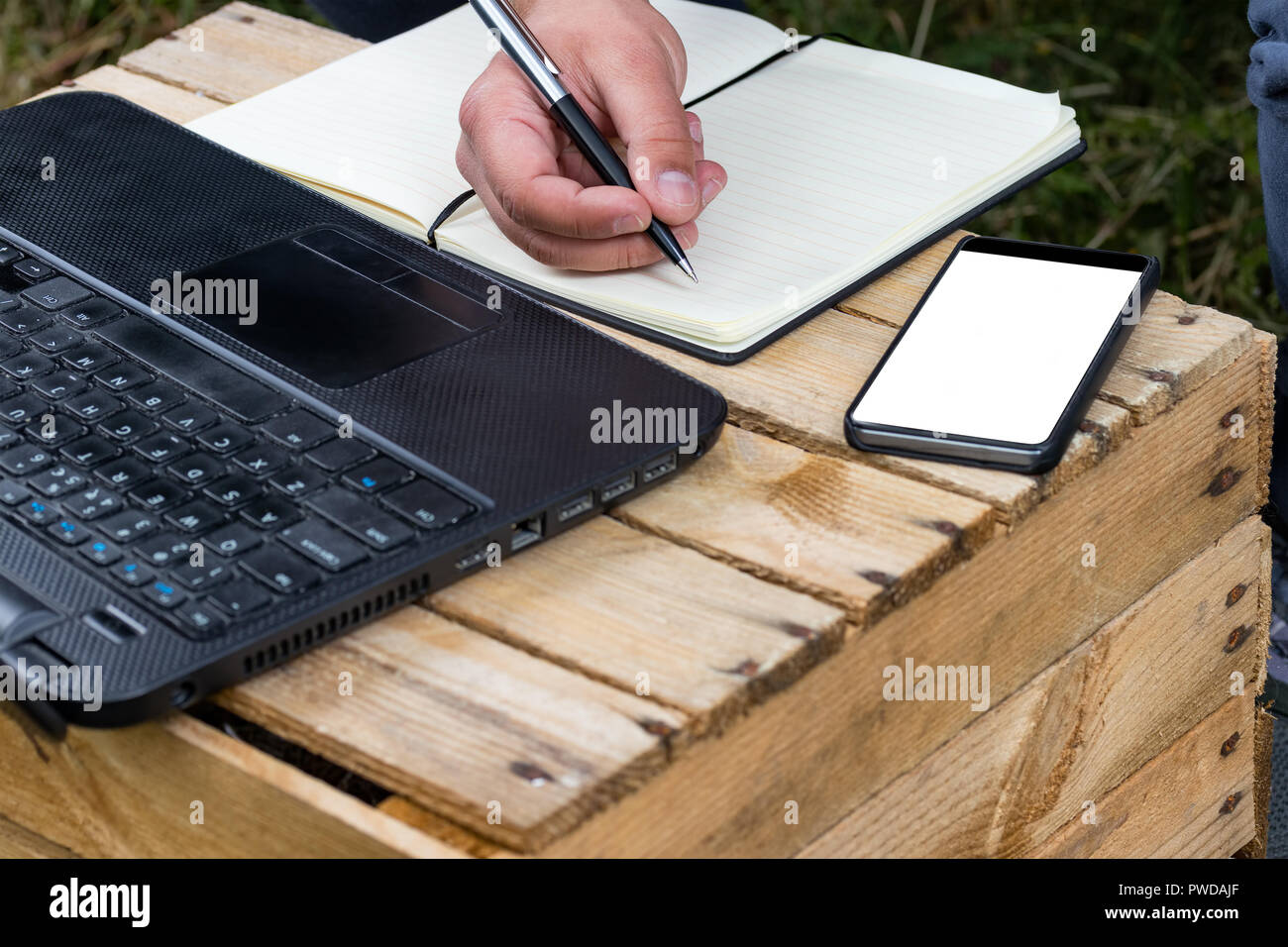 Hand Writing In A Notepad With Laptop And Bezel Less Smartphone