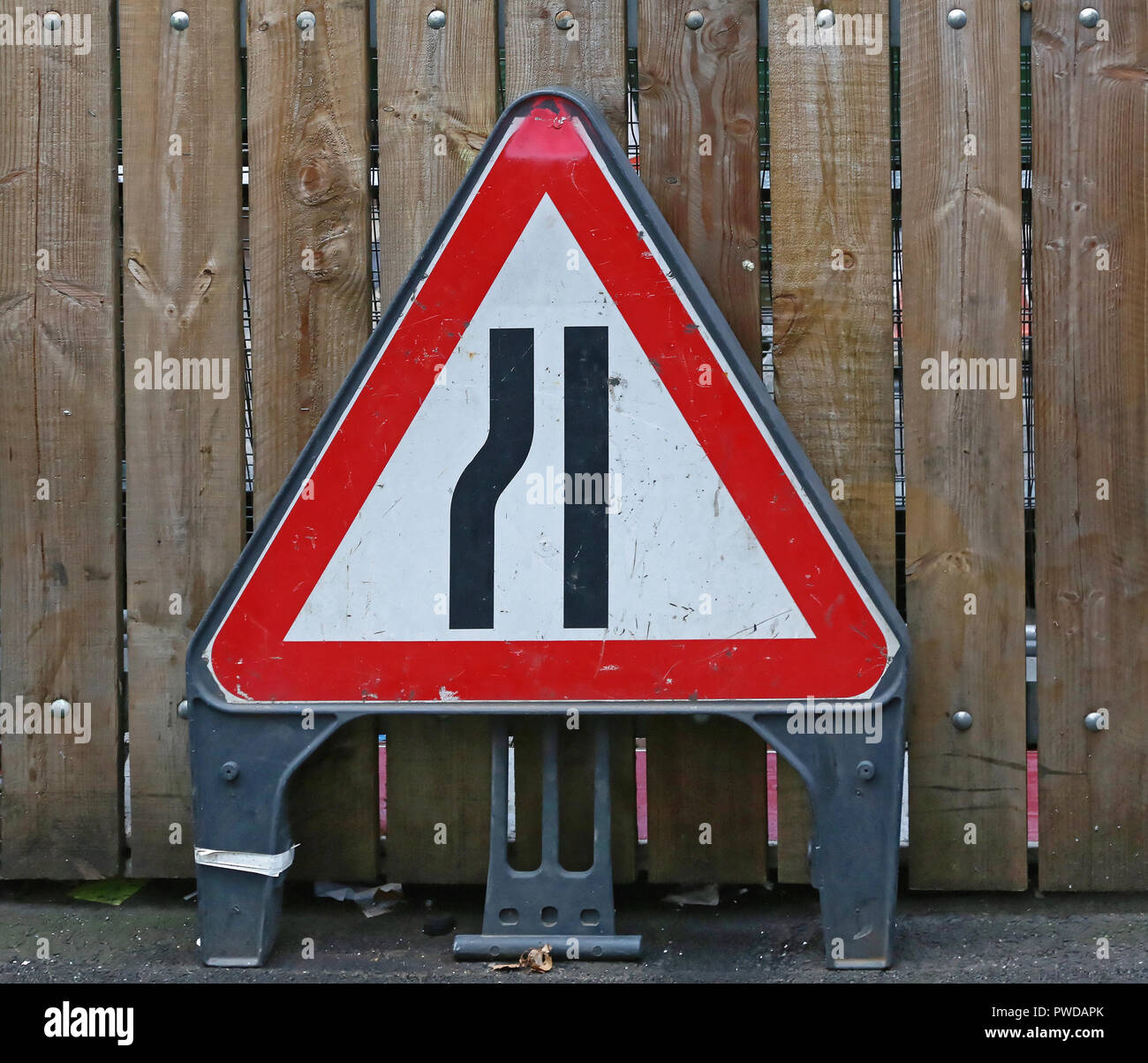 Road Narrows Traffic Sign Warning at Fence Stock Photo