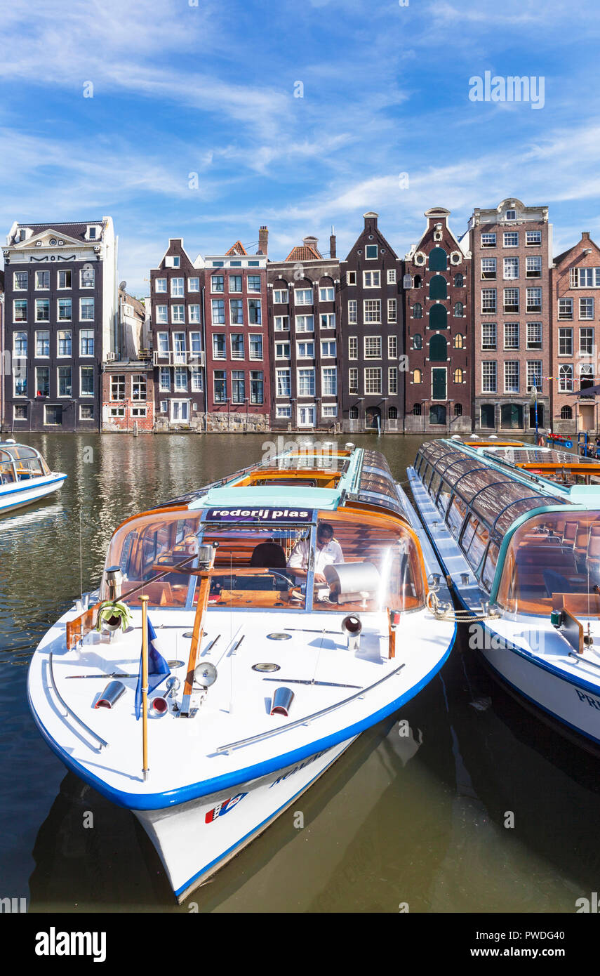 Amsterdam houses dutch architecture Damrak a partially filled in canal with canal tour boats by the canal Amsterdam Holland Netherlands EU Europe Stock Photo