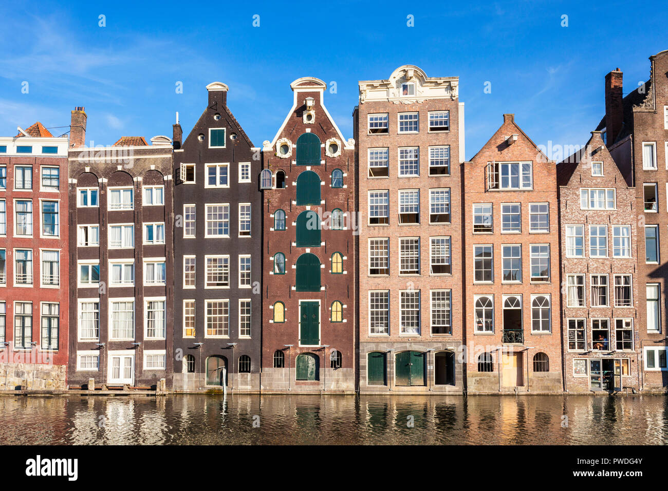 Amsterdam houses on Damrak a partially filled in canal dancing houses with dutch architecture by the canal Amsterdam Holland Netherlands EU Europe Stock Photo