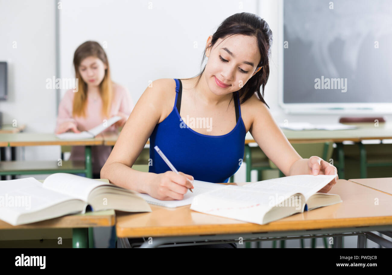 Smiling schoolgirl is learning at the desk in the class Stock Photo - Alamy
