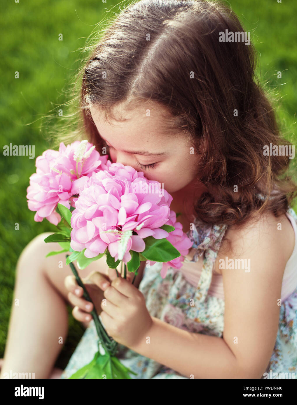 Pretty and cute child holding and sniffing flowers Stock Photo