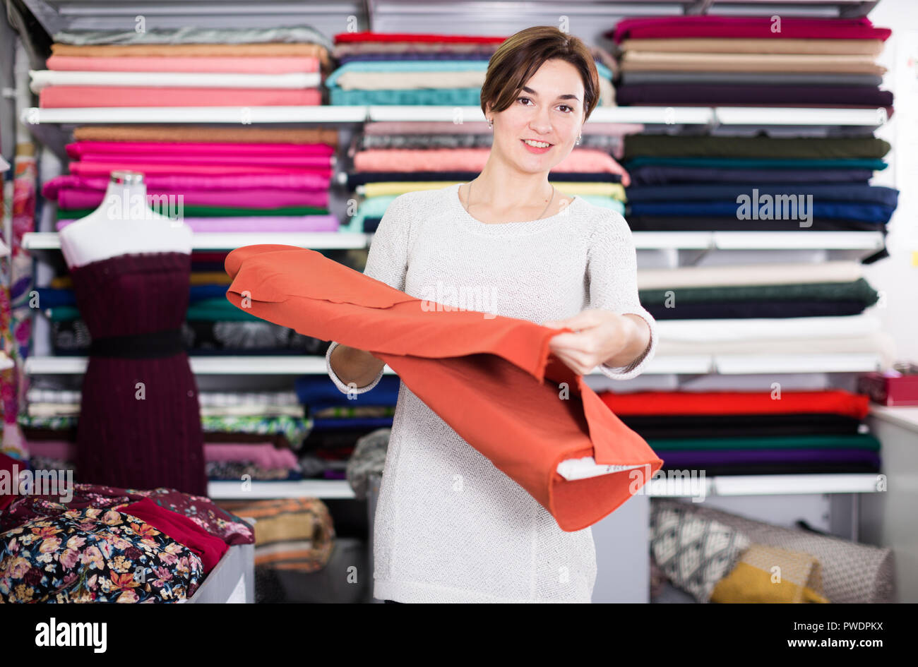 Girl customer looking for beautiful fabric in drapery shop Stock Photo
