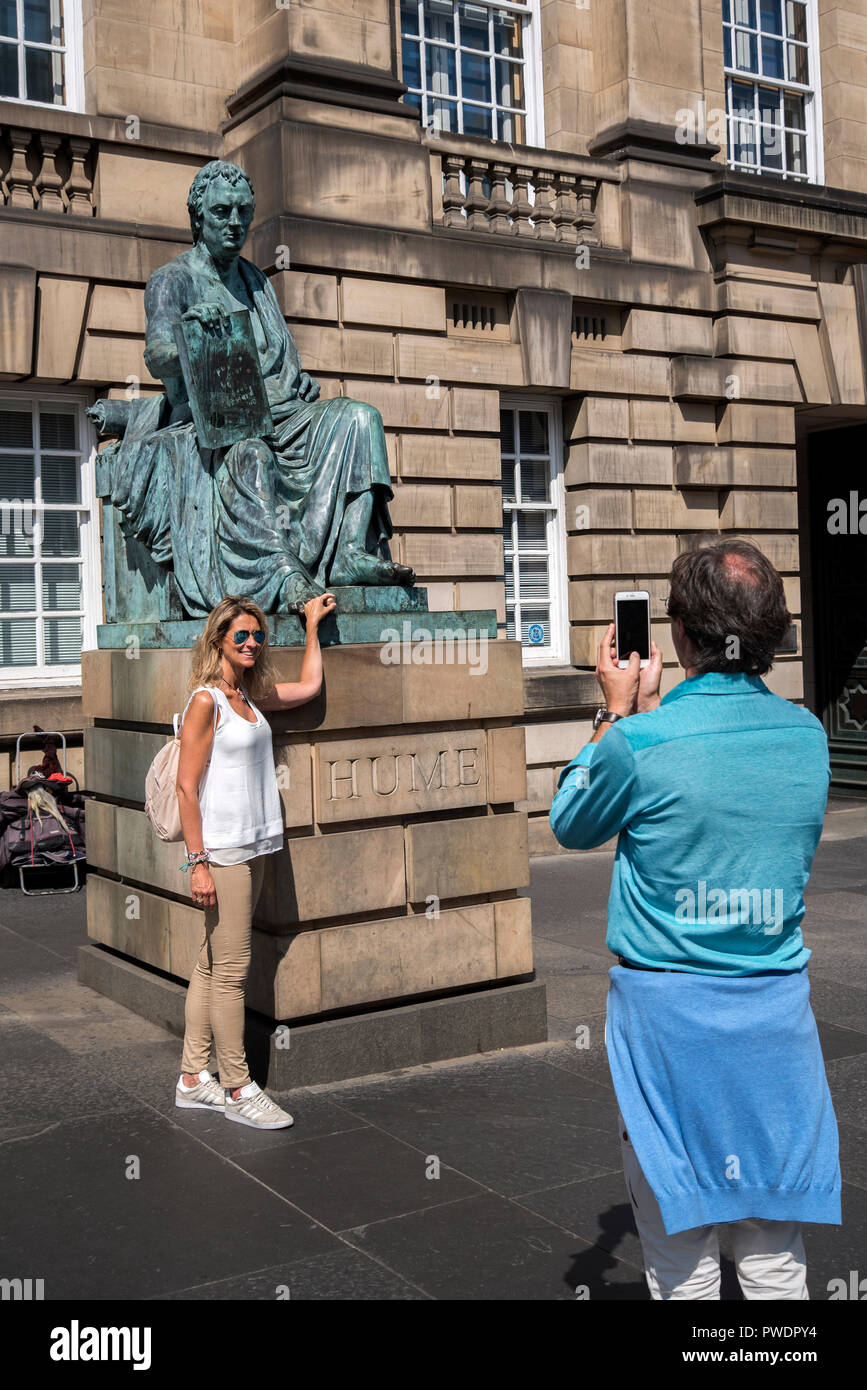 A female tourist rubs the toe on the statue of the Scottish Philosopher David Hume on Edinburgh's Royal Mile. Stock Photo