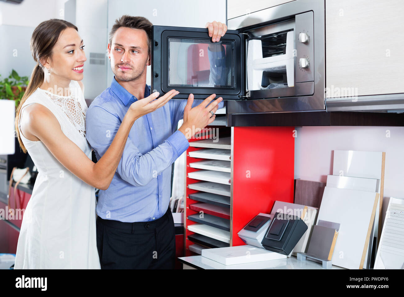 Young happy couple choosing microwave in household appliance section in furnishing store Stock Photo