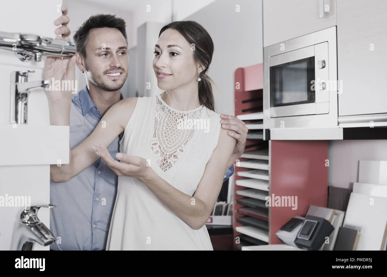 Happy family choosing faucet for kitchen in furniture workshop