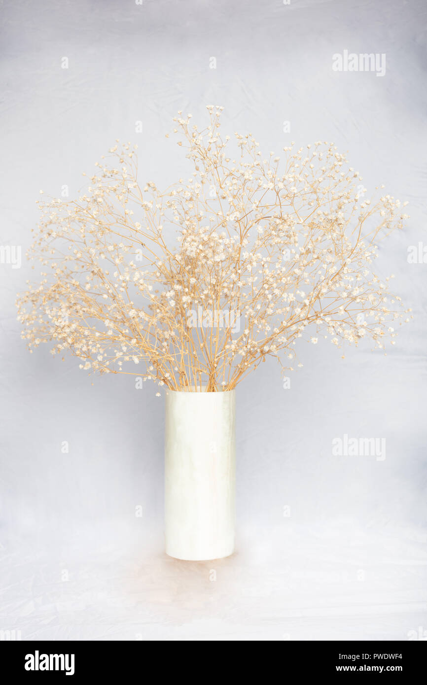 Cylindrical marble vase with a delicate flower arrangement against a