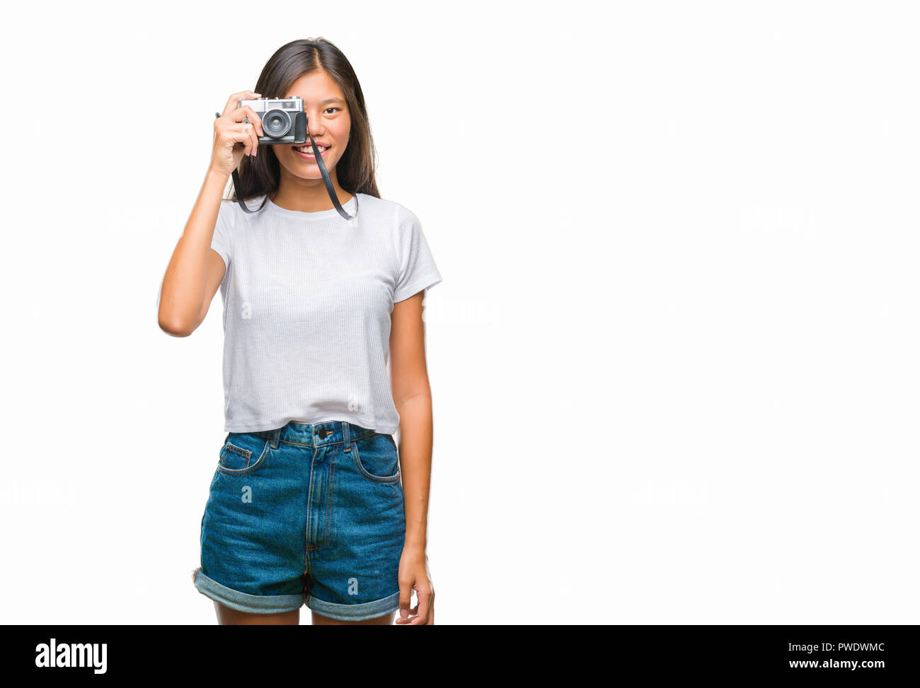 Young asian woman holding vintagera photo camera over isolated background with a happy face standing and smiling with a confident smile showing teeth Stock Photo
