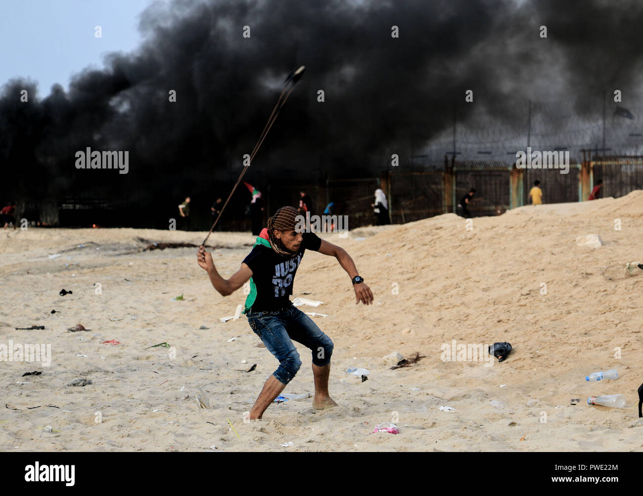 Beit Lahiya, The Gaza Strip, Palestine. 15th Oct, 2018. A Palestinian protestor throw a stone at Israeli troops during a demonstration northern the Gaza strip on the beach of Beit Lahiya. Credit: Mahmoud Khattab/Quds Net News/ZUMA Wire/Alamy Live News Stock Photo
