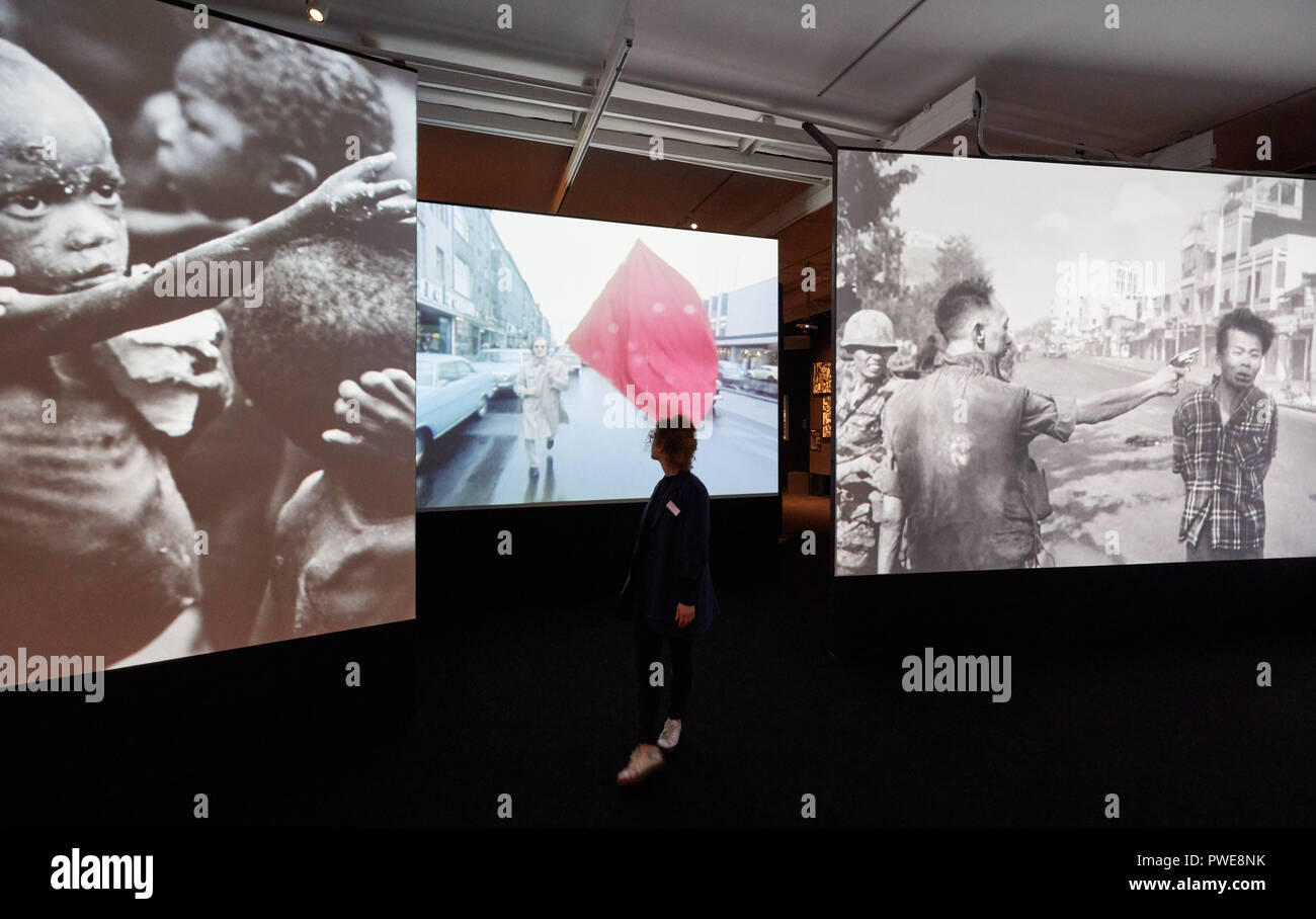 16 October 2018, Hamburg: An employee walks past video screens in the exhibition '68. Pop and Protest' at the Museum für Kunst und Gewerbe. In the middle is the film 'Farbtest - Rote Fahne, 1968' by Gerd Conradt. On the left is 'Drought and famine in the Sahel', picture alliance/dpa, and on the right 'Execution of a Vietcong fighter by the South Vietnamese police chief of Saigon', Eddie Adams. The exhibition runs from 18.10.2018 to 17.03.2019. Photo: Georg Wendt/dpa Stock Photo