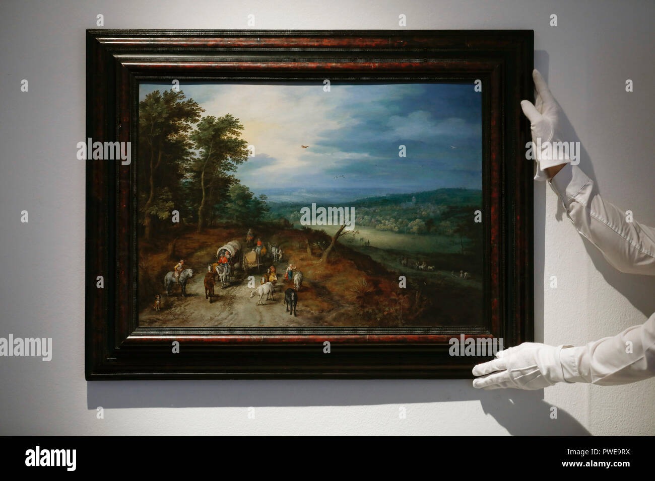 London, UK, 16th Oct 2018. A Christie's employee holds Dutch master Jan Breughel the Elder 's works 'An extensive wooded landscapef' at Christie's AuctionHouse in London, UK, Tuesday October 16, 2017. The piece is expected to achieve up to £5million when it comes to auction as part of the Albada Jelgersma Collection sale during Christie's Classic Week in December. Photograph : Credit: Luke MacGregor/Alamy Live News Stock Photo