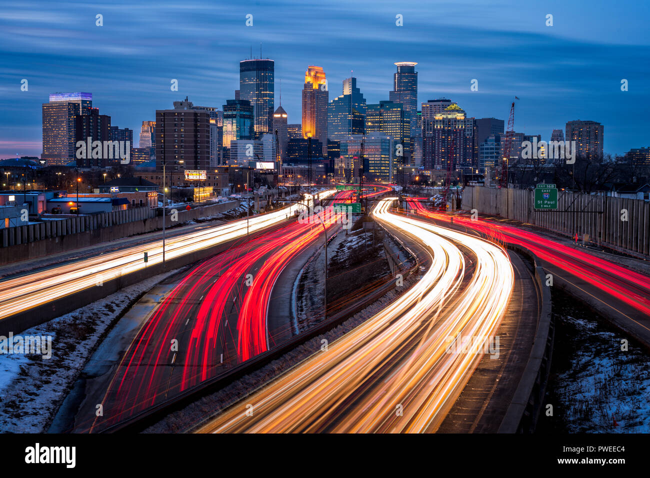 Light trails and the Minneapolis, Minnesota skyline at dusk as seen from the 24th Street walking bridge over Interstate 35W. Stock Photo