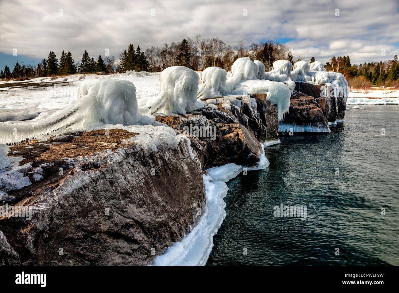 Waves from an early spring storm coat the shoreline of Gooseberry Falls State Park in a layer of ice. Stock Photo
