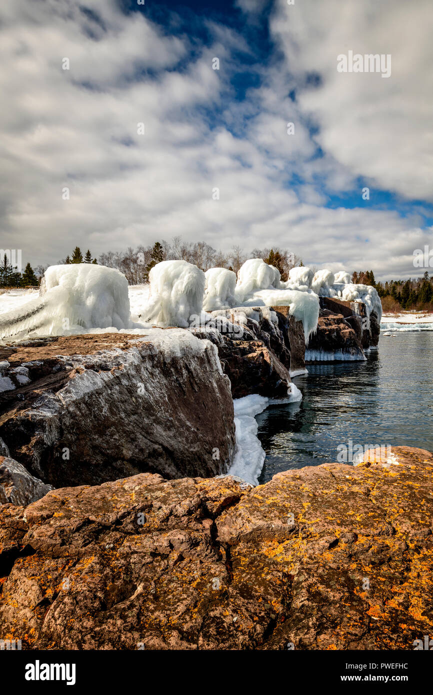 Waves from an early spring storm coat the shoreline of Gooseberry Falls State Park in a layer of ice. Stock Photo