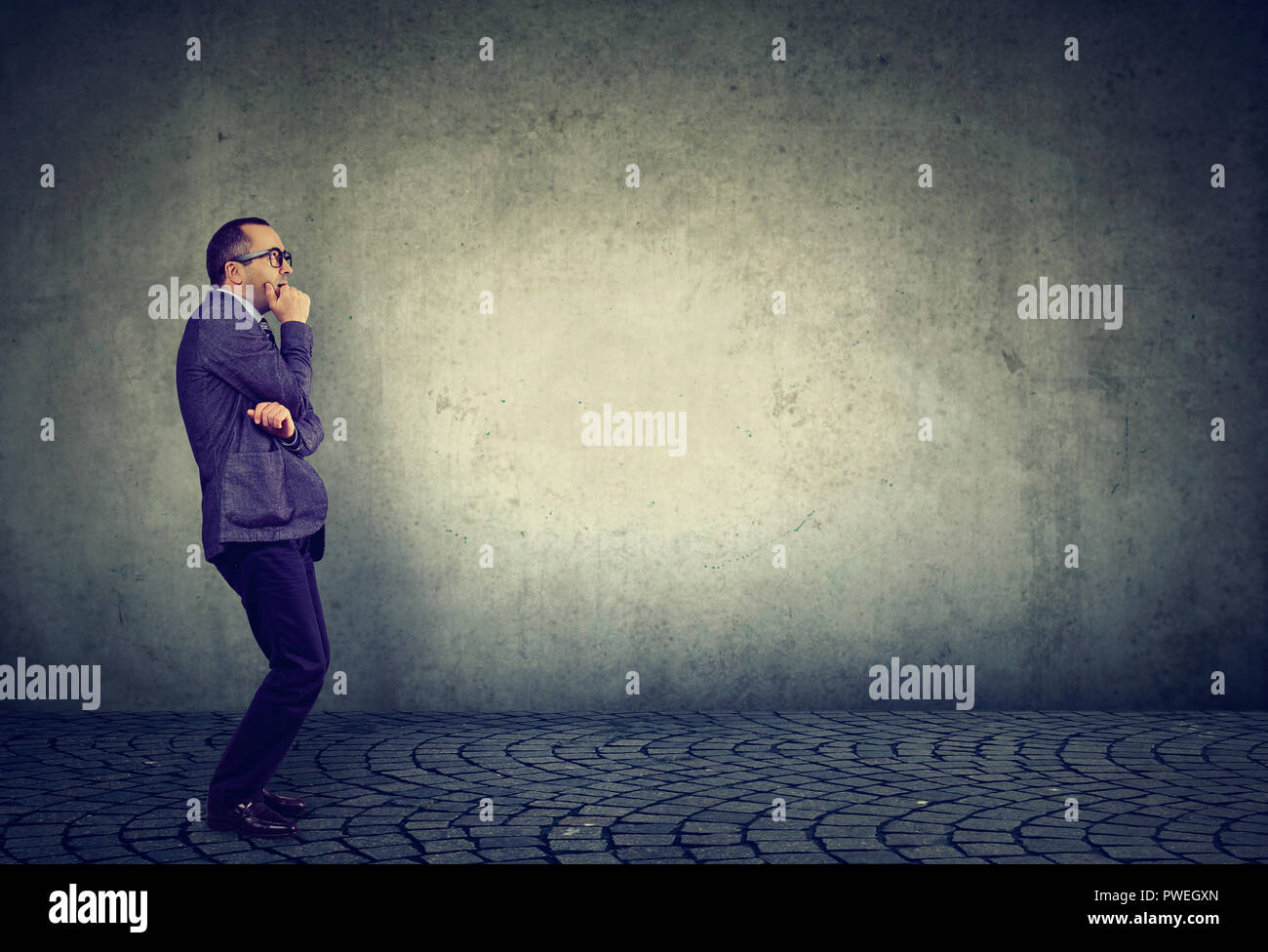 Side view of anxious businessman in fear standing nervously on gray