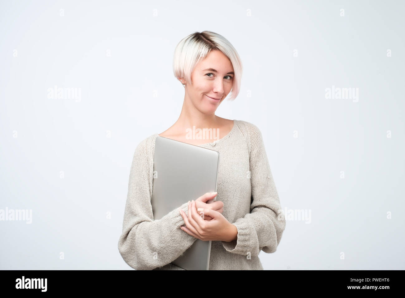 Cheerful Young Woman With Dyed Short Hair Standing Holding Laptop